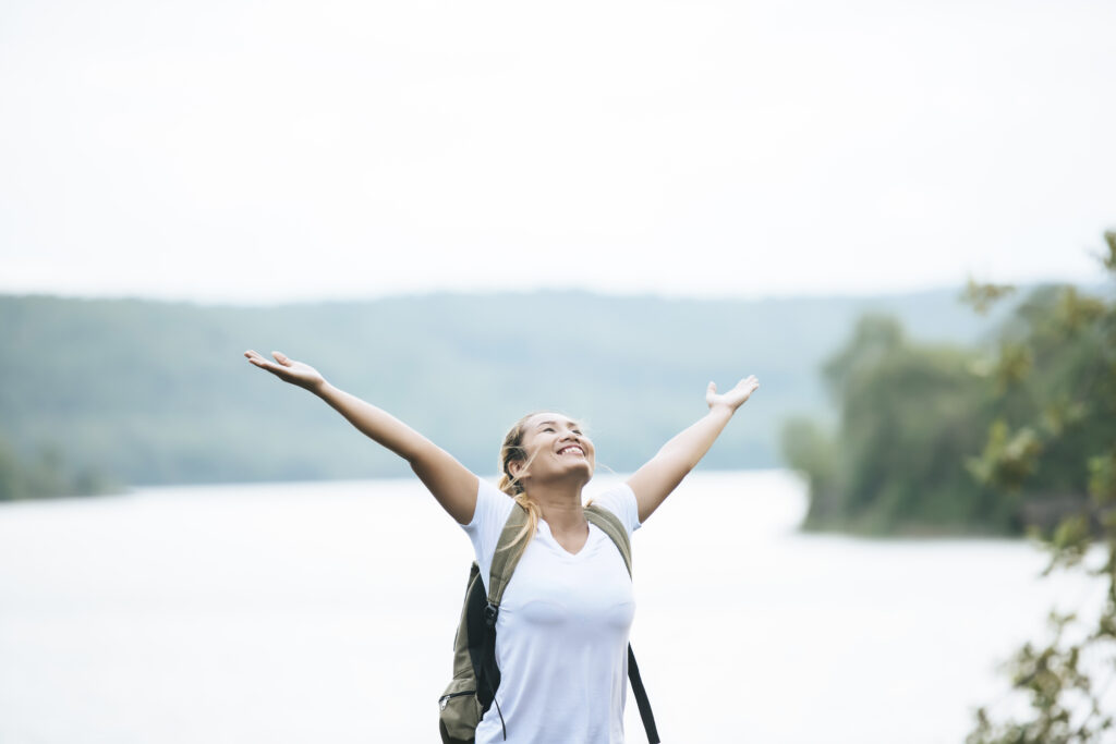 Tourist girl with arms happy with nature near the river. Travel
